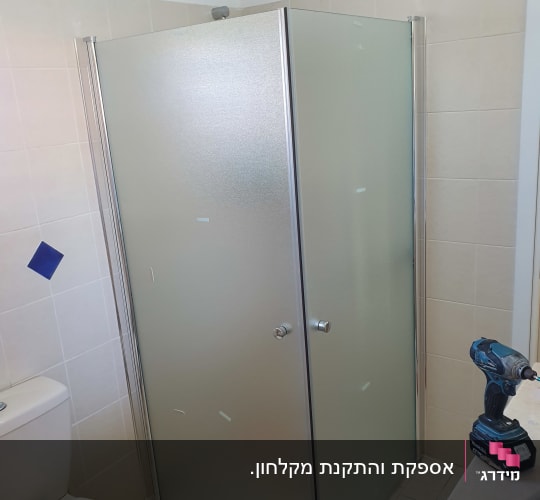 מקלחון זכוכית עם דלתות מתכת בחדר אמבטיה
